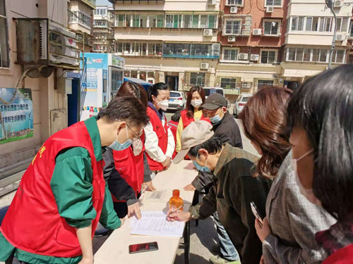 图为党员干部帮助社区居民进行疫苗接种信息登记